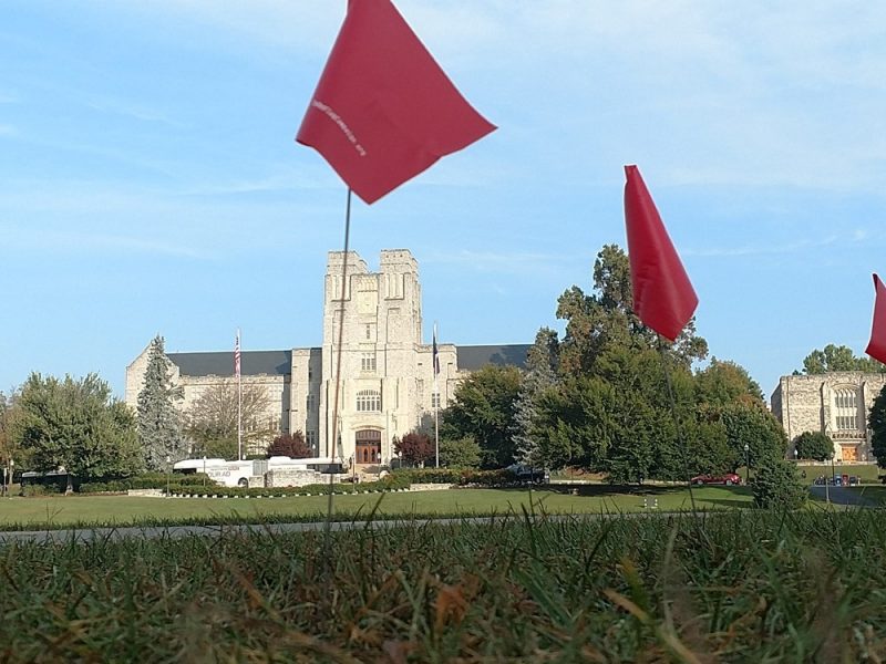 Photo of red flags in the foreground and Burruss Hall in the background