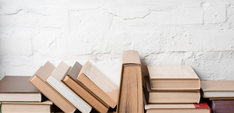 Books laid out in front of a white brick wall.